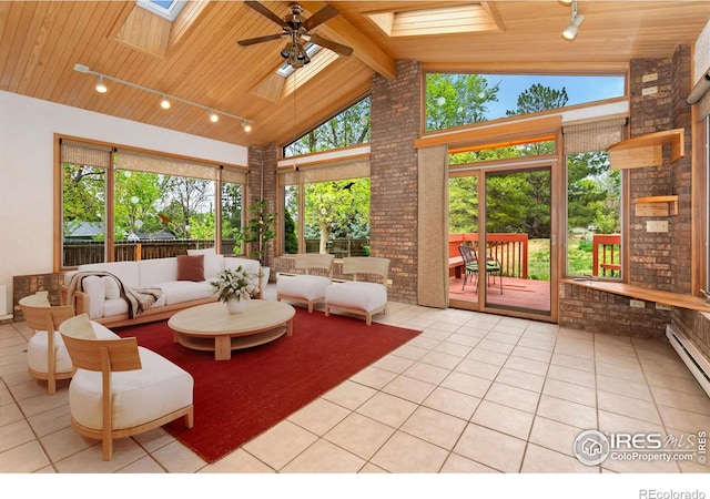 sunroom / solarium featuring a skylight, tile patterned floors, wood ceiling, rail lighting, and plenty of natural light