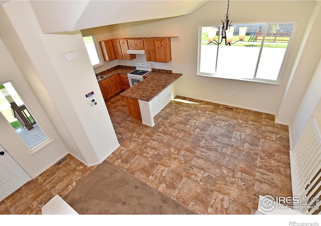 8516 8th St, Greeley, CO 80634 - kitchen with white electric range oven, brown cabinets, a peninsula, plenty of natural light, and lofted ceiling