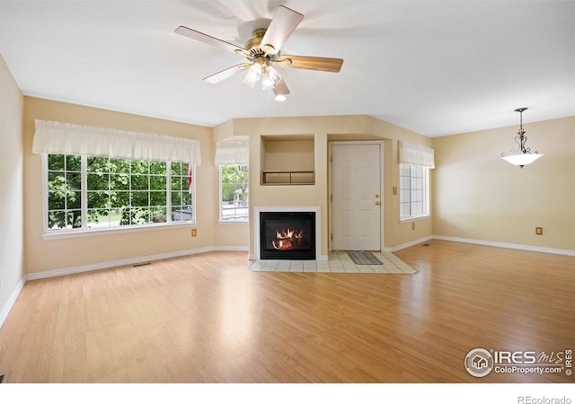 unfurnished living room with wood finished floors, baseboards, a fireplace with flush hearth, and ceiling fan