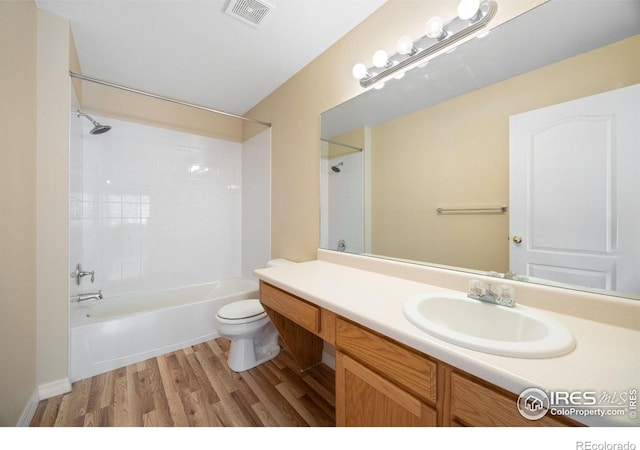 bathroom with wood finished floors, toilet, vanity, and shower / bath combination