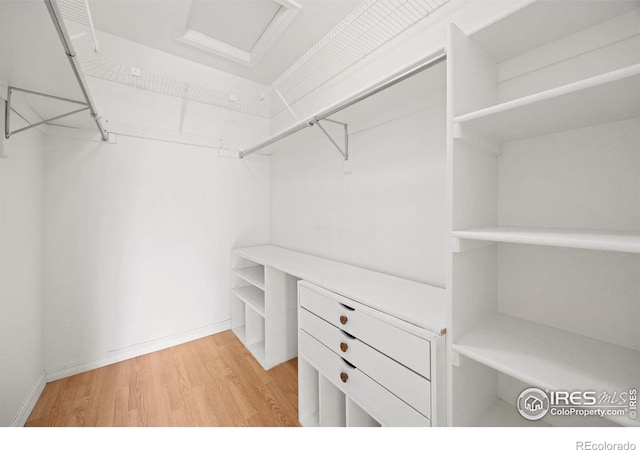 walk in closet with light wood-style flooring and attic access