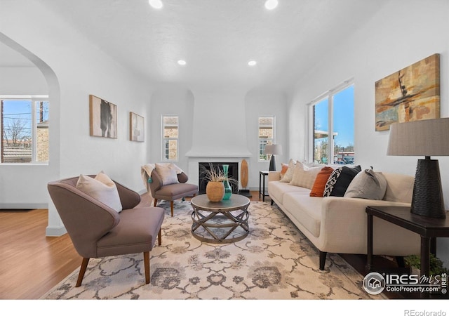living room featuring healthy amount of natural light, recessed lighting, arched walkways, and wood finished floors