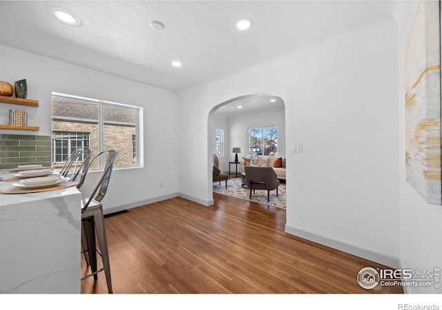 dining area with arched walkways, wood finished floors, recessed lighting, and baseboards