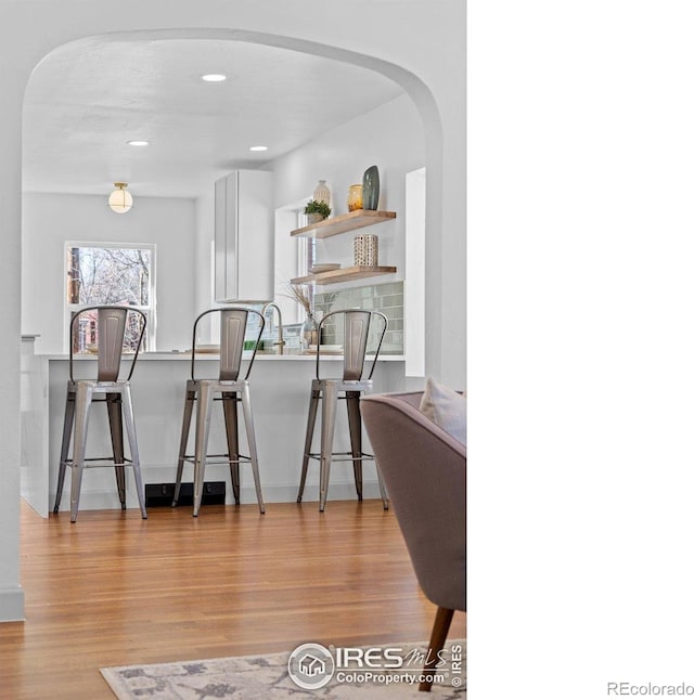 dining space with wood finished floors, arched walkways, and recessed lighting