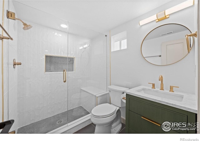 bathroom featuring toilet, a shower stall, and vanity