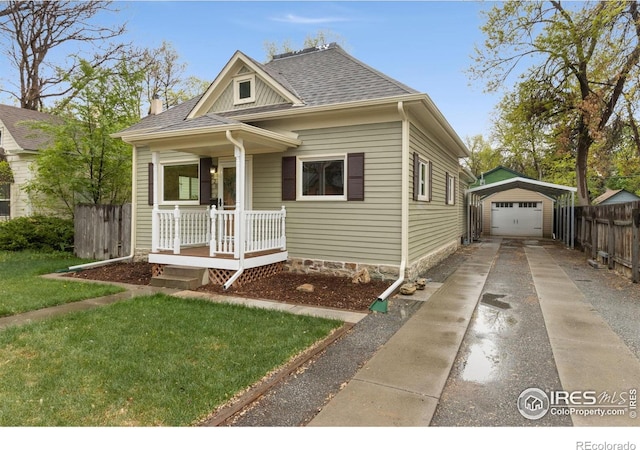 bungalow featuring concrete driveway, a porch, a detached garage, an outbuilding, and roof with shingles