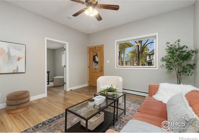 living area featuring wood finished floors, baseboard heating, ceiling fan, and baseboards