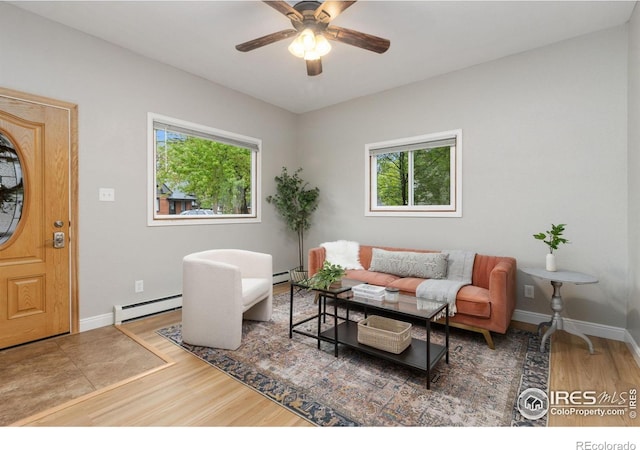 living room featuring wood finished floors, baseboard heating, a ceiling fan, and baseboards