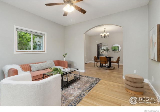living room with arched walkways, wood finished floors, ceiling fan, baseboards, and a chandelier
