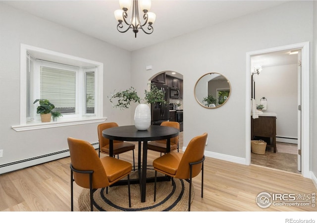 dining area with a baseboard radiator, light wood-style floors, a chandelier, arched walkways, and baseboards