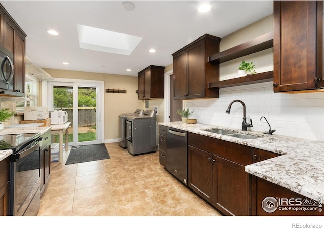 kitchen with washing machine and dryer, stainless steel appliances, a skylight, a sink, and dark brown cabinets