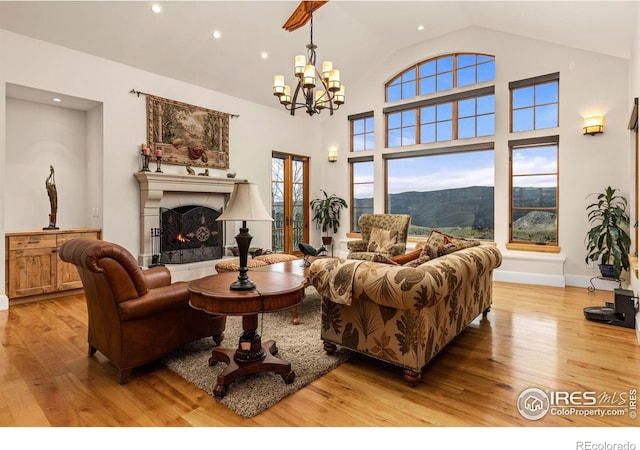 living room featuring light wood-style flooring, a chandelier, a lit fireplace, recessed lighting, and baseboards