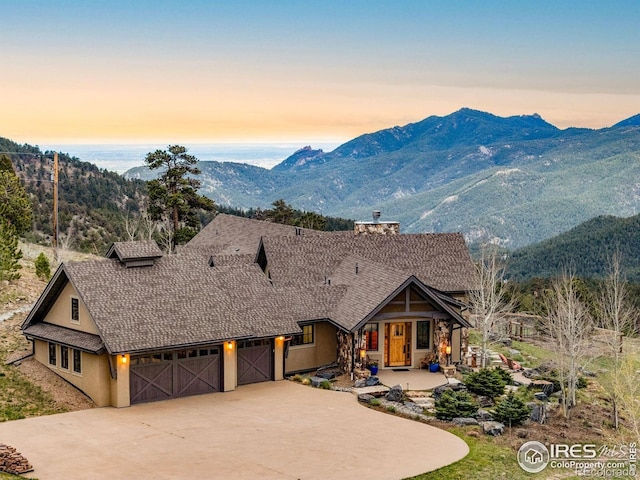 view of front of property with a chimney, an attached garage, driveway, and a mountain view