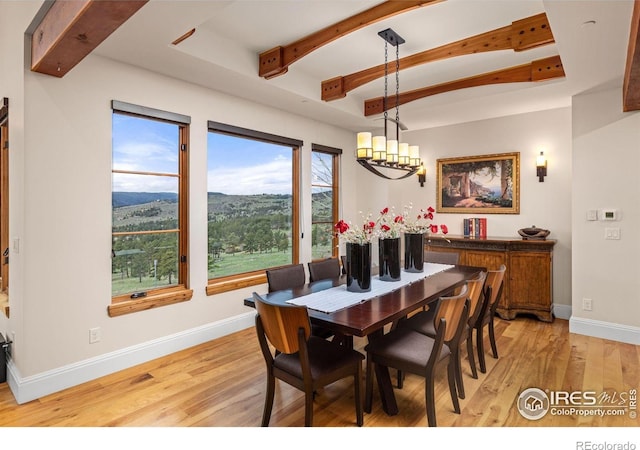 dining area with a chandelier, light wood-style flooring, beam ceiling, and baseboards