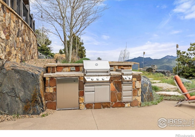 view of patio with an outdoor kitchen, area for grilling, and a mountain view