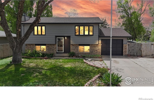 1240 3rd St, Eaton, CO 80615 - raised ranch with concrete driveway, an attached garage, brick siding, and a chimney