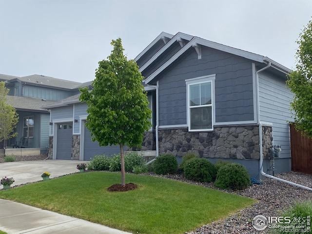 view of front of property with concrete driveway, a front lawn, stone siding, and a garage
