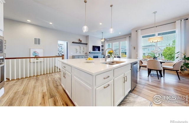 kitchen featuring a sink, light wood-type flooring, stainless steel appliances, a ceiling fan, and pendant lighting