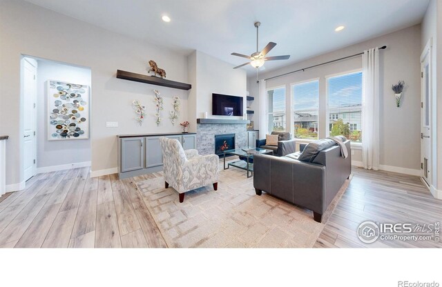living room with a ceiling fan, light wood-style flooring, a fireplace, baseboards, and recessed lighting