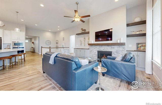living room featuring a fireplace, a ceiling fan, light wood finished floors, recessed lighting, and baseboards