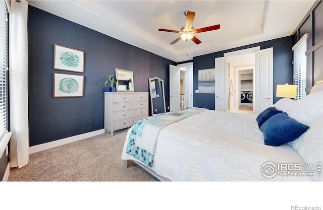 bedroom featuring carpet flooring, a raised ceiling, baseboards, ceiling fan, and washer / clothes dryer
