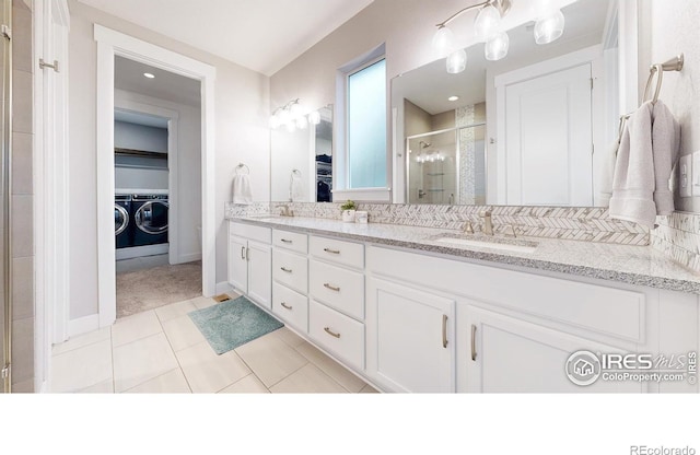 full bathroom with washer and clothes dryer, a shower stall, double vanity, tile patterned flooring, and a walk in closet