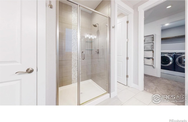 full bath featuring washing machine and dryer, a stall shower, tile patterned floors, and baseboards