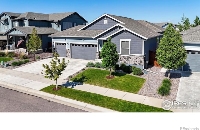 2137 Setting Sun Dr, Windsor, CO 80550 - craftsman-style house featuring an attached garage, stone siding, driveway, a shingled roof, and a front lawn