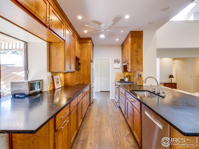 700 Poplar Ave, Boulder, CO 80304 - kitchen featuring stainless steel appliances, a sink, a peninsula, wood finished floors, and dark countertops
