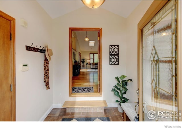 hallway featuring vaulted ceiling and baseboards