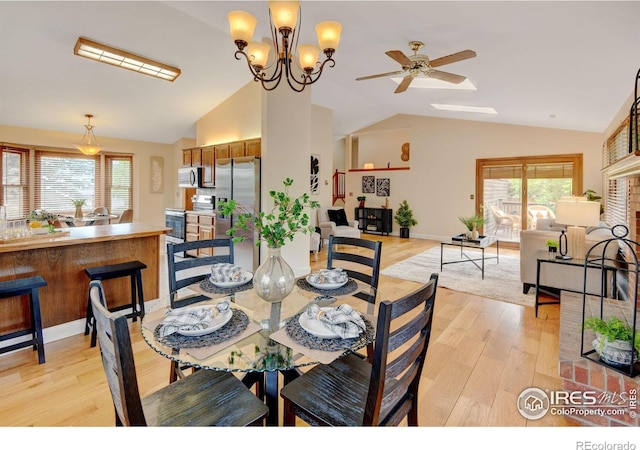 dining space with vaulted ceiling, light wood-style flooring, ceiling fan, a chandelier, and baseboards