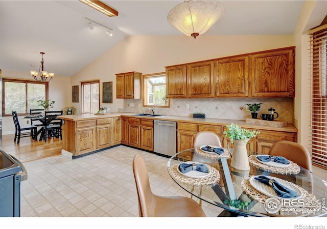 kitchen featuring dishwasher, rail lighting, lofted ceiling, a sink, and a peninsula