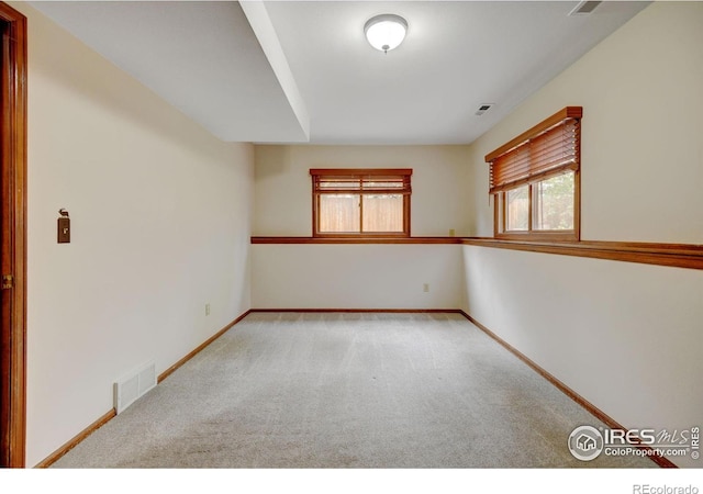 carpeted spare room featuring plenty of natural light and baseboards
