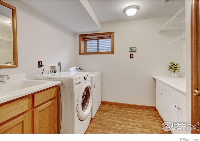 laundry room with independent washer and dryer, light wood-type flooring, cabinet space, and baseboards