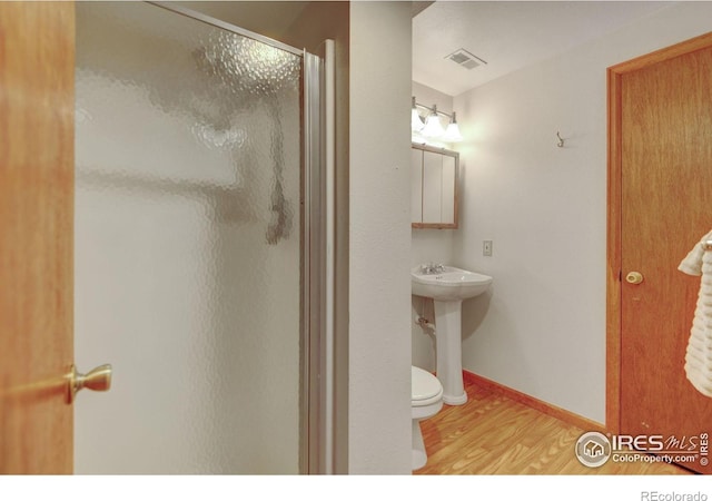full bathroom featuring a stall shower, wood finished floors, a sink, toilet, and baseboards