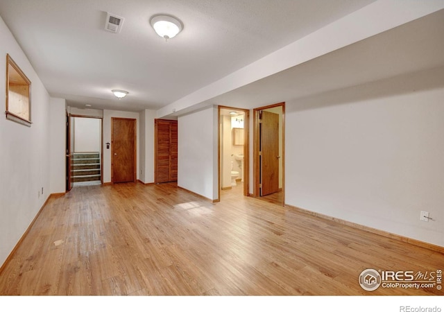 spare room with stairway, light wood-style floors, and baseboards