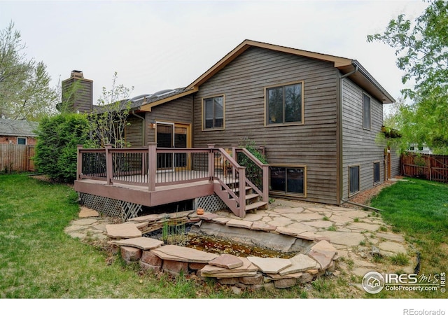 rear view of house featuring a wooden deck, a chimney, and a patio