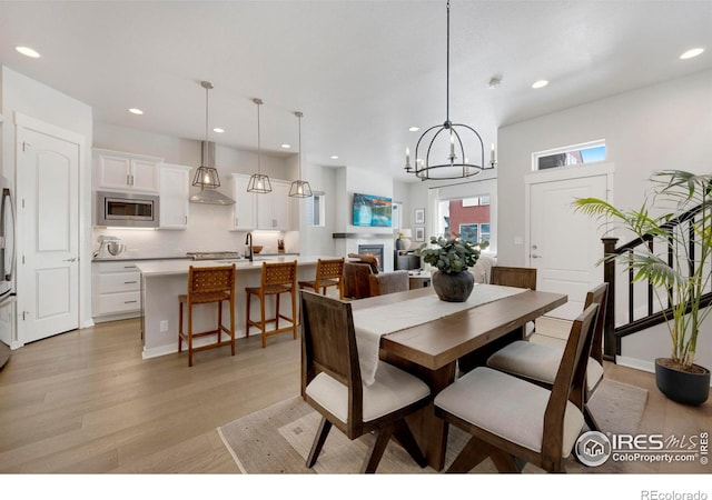dining area with light wood-type flooring, recessed lighting, and a chandelier