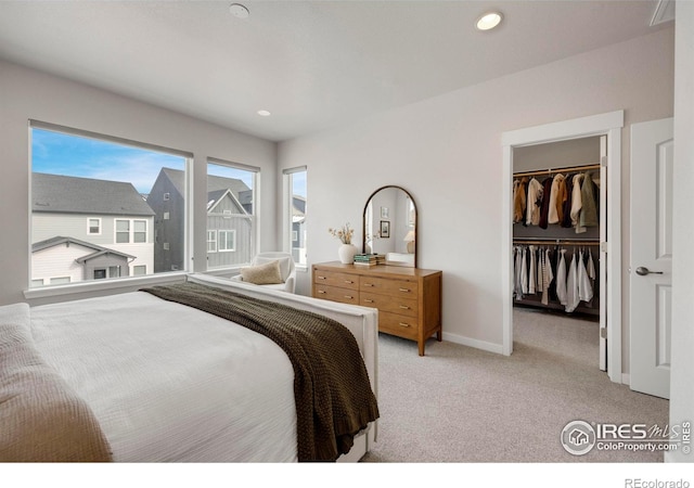 bedroom featuring light carpet, a spacious closet, baseboards, recessed lighting, and a closet