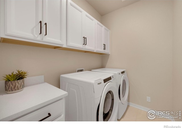 washroom featuring cabinet space, washing machine and dryer, baseboards, and light tile patterned floors