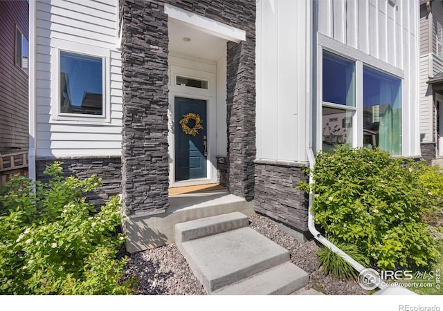 view of exterior entry with stone siding and board and batten siding