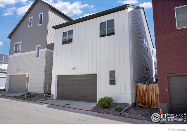 view of home's exterior with board and batten siding, a garage, fence, and concrete driveway