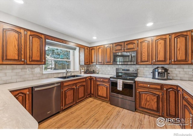 4880 Filbert Dr, Loveland, CO 80538 - kitchen with appliances with stainless steel finishes, a sink, light wood finished floors, light countertops, and brown cabinetry