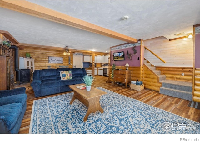 1810 N Ridge Ln, Estes Park, CO 80517 - living area featuring log walls, wood finished floors, a wood stove, stairway, and beam ceiling