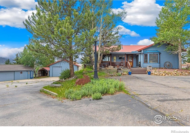 1810 N Ridge Ln, Estes Park, CO 80517 - single story home featuring a detached garage, covered porch, an outbuilding, a metal roof, and driveway