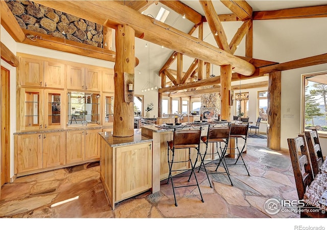 6553 Sunshine Canyon Dr, Boulder, CO 80302 - kitchen with light brown cabinetry, high vaulted ceiling, stone countertops, stone flooring, and a breakfast bar