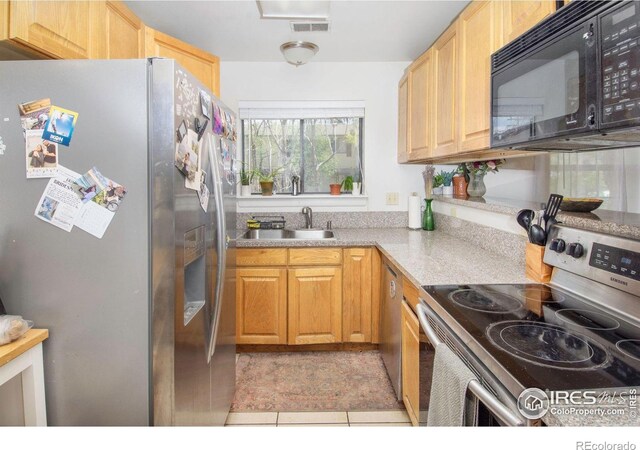 kitchen with stainless steel appliances, a sink, and light tile patterned floors