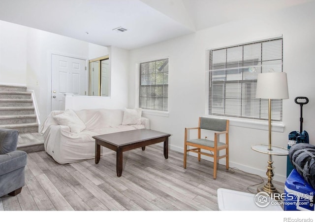 living room featuring light wood finished floors, stairway, and baseboards