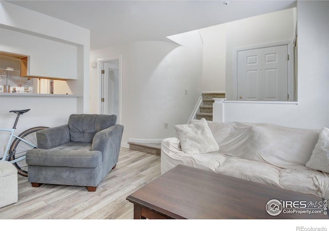 living area with light wood finished floors and stairway