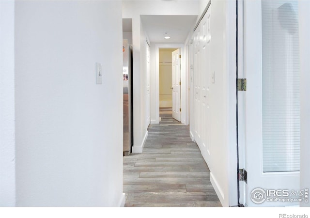corridor featuring light wood-type flooring and baseboards